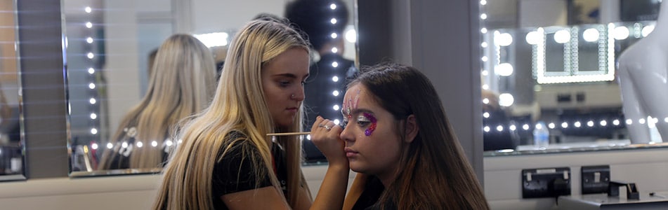Theatrical Makeup students paining students face.